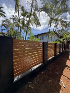 A modern horizontal slat wood fence with dark support pillars installed by A&D Services in Kapolei, HI.