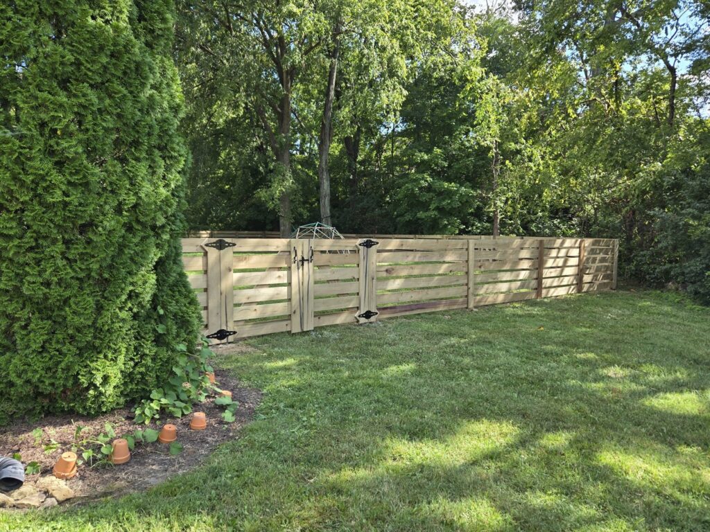 A horizontal slat wood fence with a double gate in a residential backyard by Shatkoff Fencing in Louisville, KY.