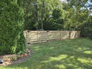A horizontal slat wood fence with a double gate in a residential backyard by Shatkoff Fencing in Louisville, KY.