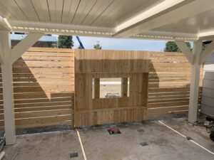 Custom horizontal slat wood fence with a window opening under a patio cover by Louis Fence installations & repairs in Fall River, MA