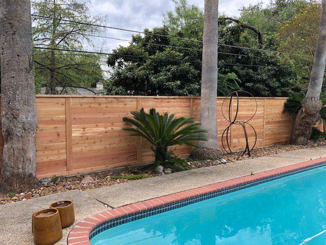 A modern horizontal slat wood fence installed alongside a swimming pool by City Fence Co of San Antonio, TX