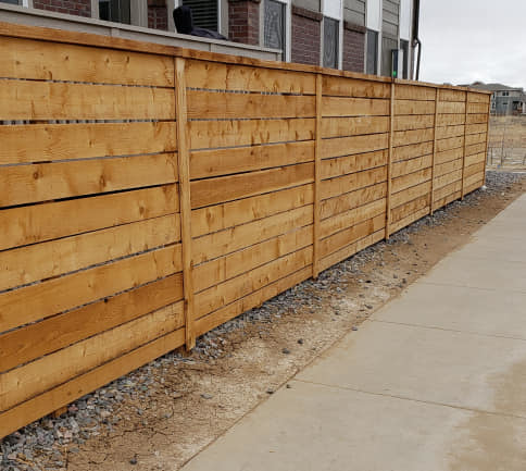 A modern horizontal slat wood fence installed along a sidewalk, completed by JBC Services LLC in Milwaukee, WI.