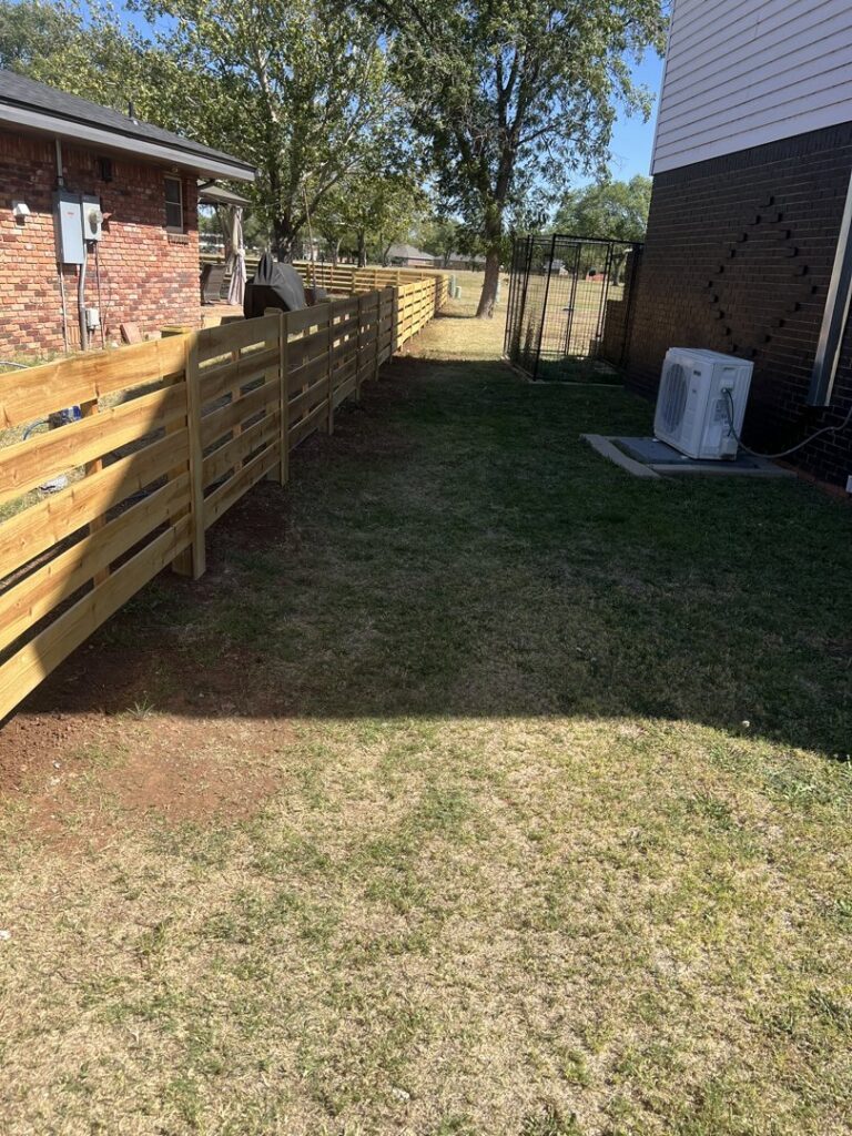 A newly installed horizontal slat wooden fence in a residential backyard, constructed by DC Fencing LLC in Clovis, NM.