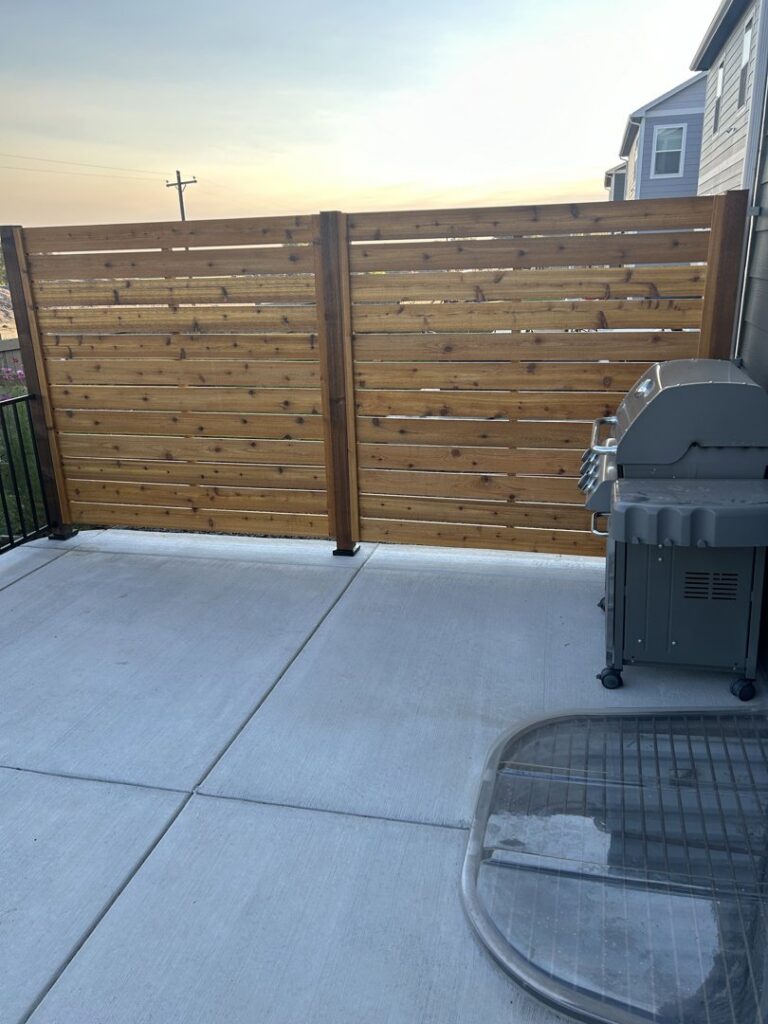 A modern horizontal slat wooden privacy fence installed on a patio, showcasing work by North CO Fence & Deck in Greeley, CO.