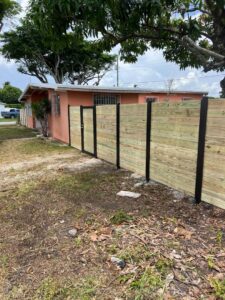 A new horizontal wood fence with black posts and a gate installed by Palm's Fence of Miami, FL.
