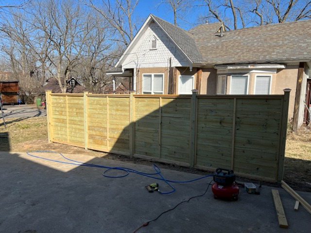 A horizontal wood fence installation with tools on the patio by Fence Solutions of NWA in Gravette, AR.