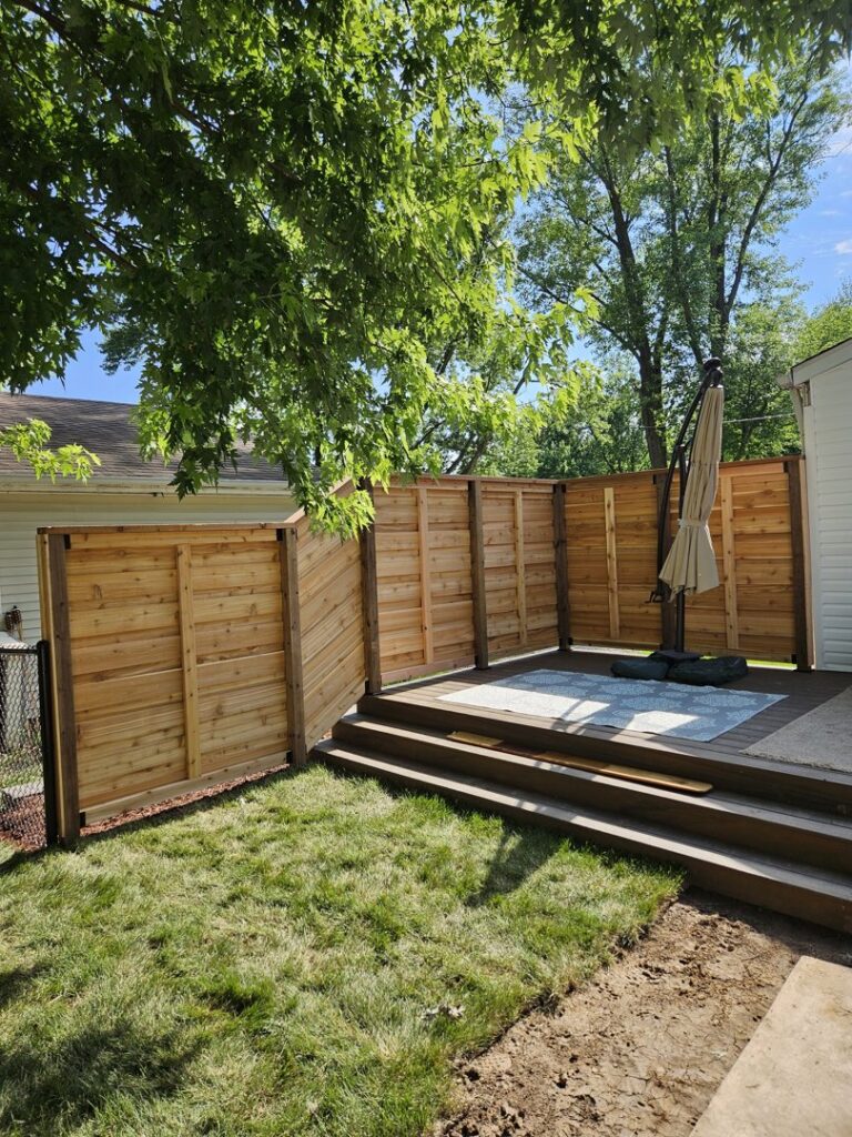 A modern horizontal wood privacy fence enclosing a deck area, installed by JM Fence Works in Davenport, IA.