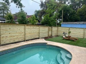 A modern horizontal wood privacy fence enclosing a swimming pool area, installed by Exacta FENCE LLC in Jacksonville, FL.