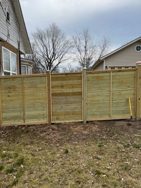 A newly installed horizontal wood slat fence with decorative post caps by Fence Solutions of NWA in Gravette, AR.