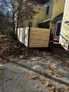 A modern horizontal wood slat fence installed as a privacy screen next to a residential building by New England landscaping and fence inc in Lynn, MA.