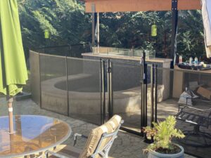 A hot tub area secured with a black mesh safety fence and gate by Golden State Baby Barrier in Sacramento, CA.