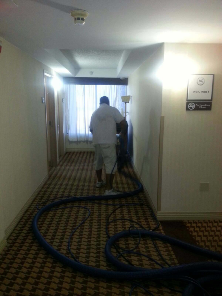 A professional cleaning a hotel hallway carpet with equipment by Apex Carpet Cleaning & Flood Restoration LLC in Phoenix, AZ