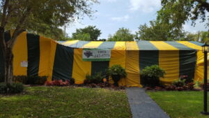 A residential house completely covered in yellow and green tarps for termite fumigation by Shield Pest Control in Homestead, FL.