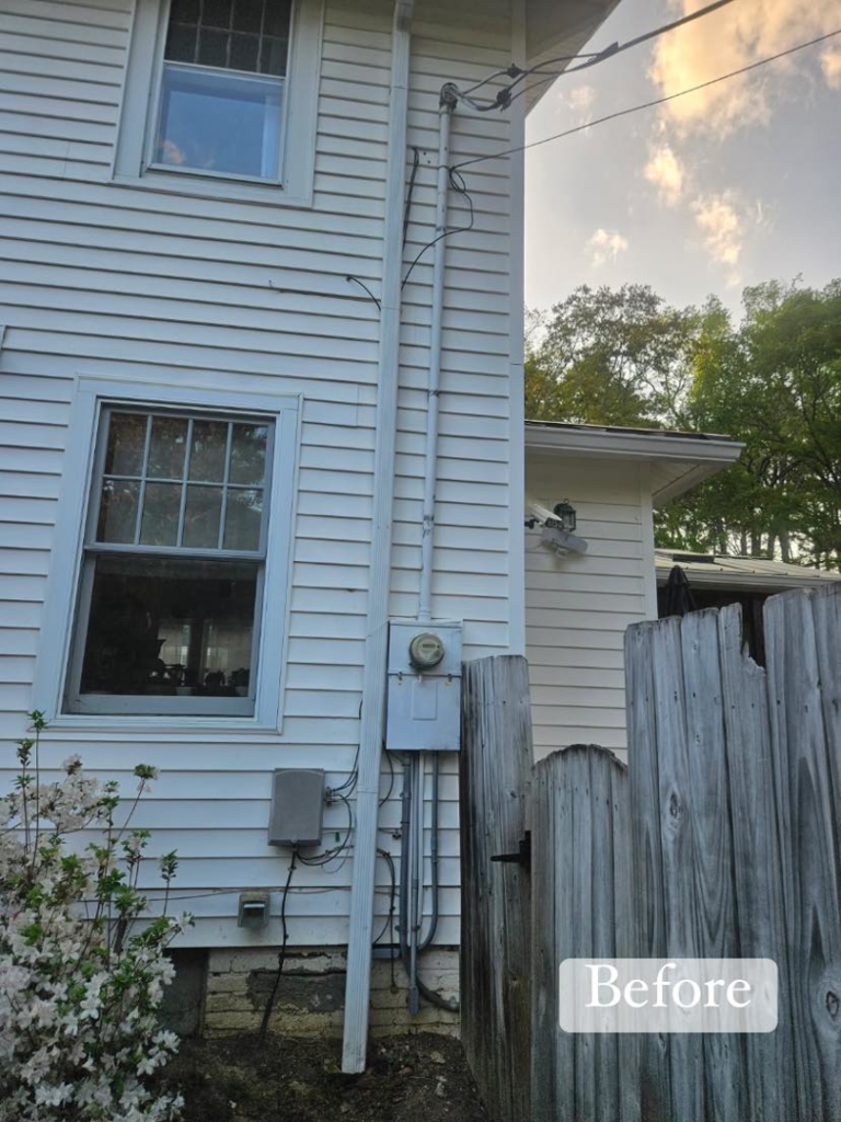 Exterior of a house showing an electrical meter and conduit before service by HLR Electric Company, LLC in Durham, NC.