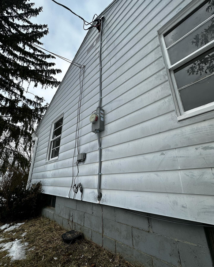 Exterior of a house showing an electrical meter and service entrance wiring installed by Elite Electric in Valley Falls, NY