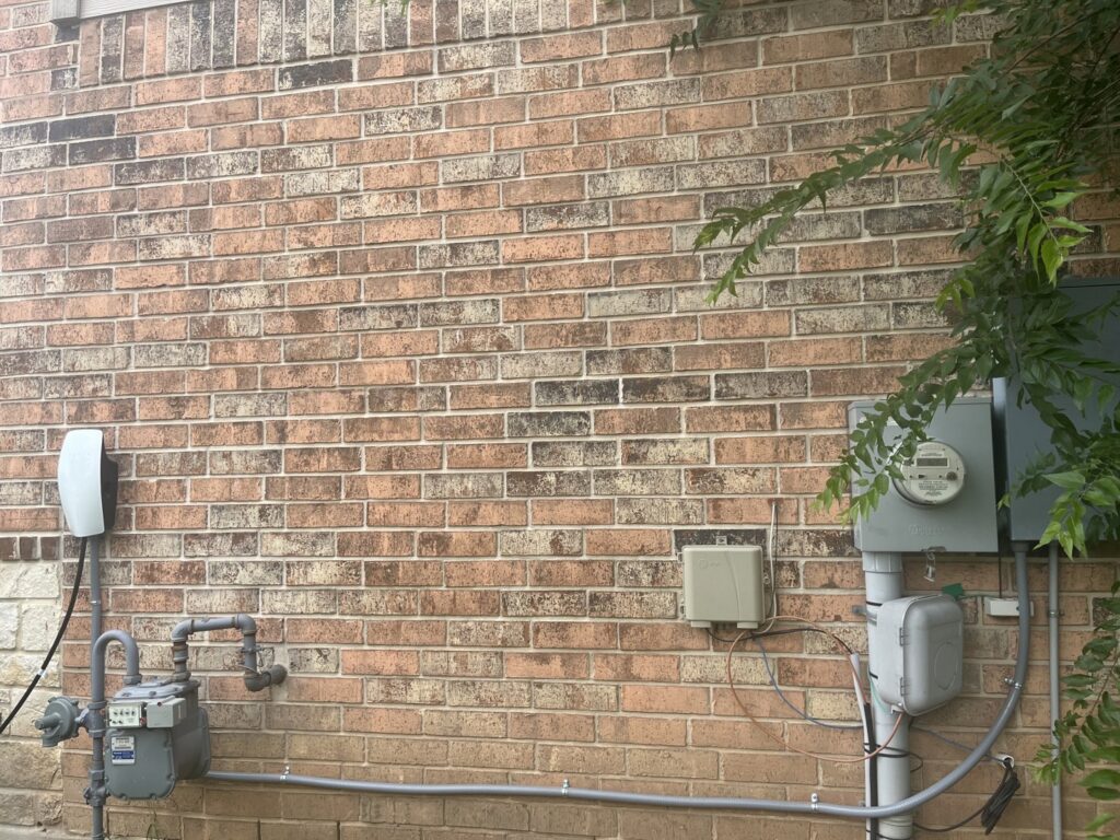 The exterior of a house showing a Tesla EV charger, electrical meter, and conduit installed by Davis Electric in Cleveland, OH.