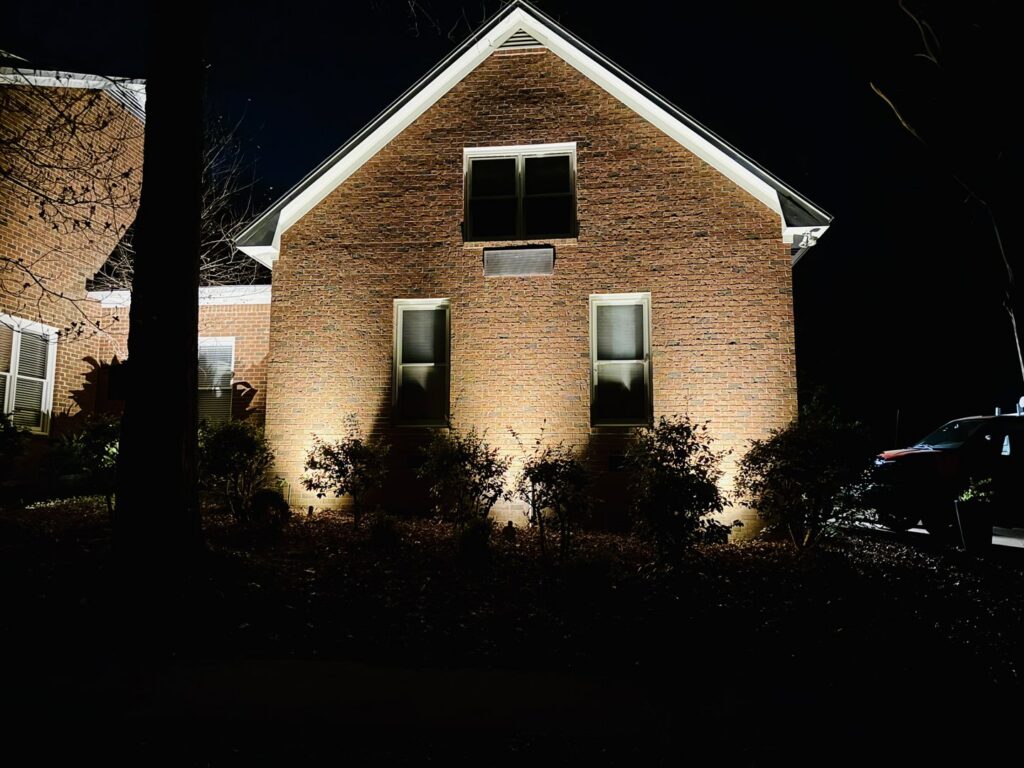 Residential house exterior illuminated at night with professional uplighting installed by Mister Sparky of Columbia in West Columbia, SC.