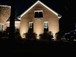 Residential house exterior illuminated at night with professional uplighting installed by Mister Sparky of Columbia in West Columbia, SC.