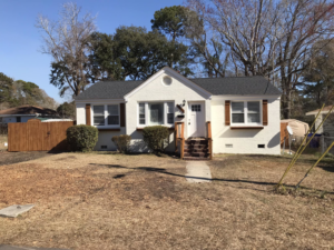 A front view of a residential house with a newly installed wooden fence on the left side by Lundquist Home Improvements in Mount Pleasant, SC.