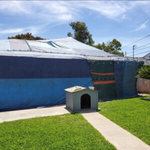 A house undergoing termite fumigation with blue and green tents, a service provided by Mecaf Termite and Pest Control in Long Beach, CA