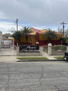 A house covered in red and yellow fumigation tents for termite treatment by Mecaf Termite and Pest Control in Long Beach, CA