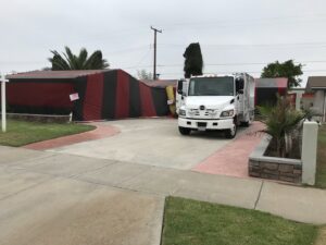 A house covered in red and black fumigation tenting with a service truck parked by Intensive Pest Control in Long Beach, CA.