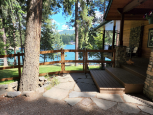 A wooden fence with wire mesh and a gate installed near a house and lake by EcoGreen Fencing in Coeur d'Alene, ID.