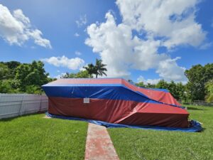 A house fully tented in red and blue tarps for termite fumigation by Monster Pest Control in Miami, FL.
