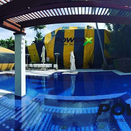 A house tented for termite treatment by PowerX Pest Control of South Florida, viewed from across a pool in Miami, FL.