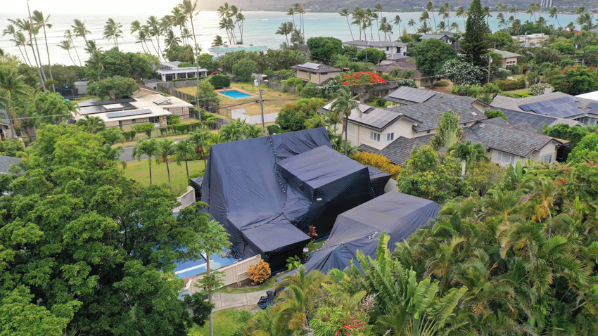 A residential house tented for termite fumigation with the ocean in the background by Oahu Termite and Pest Control in Pearl City, HI.