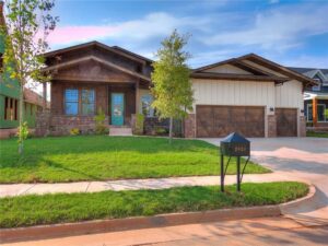 A house featuring two newly installed wooden garage doors by CCM Overhead Doors in Oklahoma City, OK