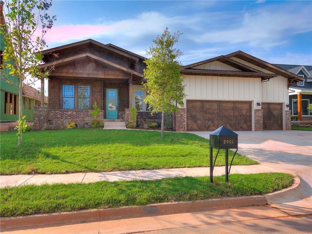 A house featuring two newly installed wooden garage doors by CCM Overhead Doors in Oklahoma City, OK