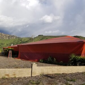 A residential house completely covered by a large orange tent for termite fumigation by United Termite Control in San Marcos, CA.