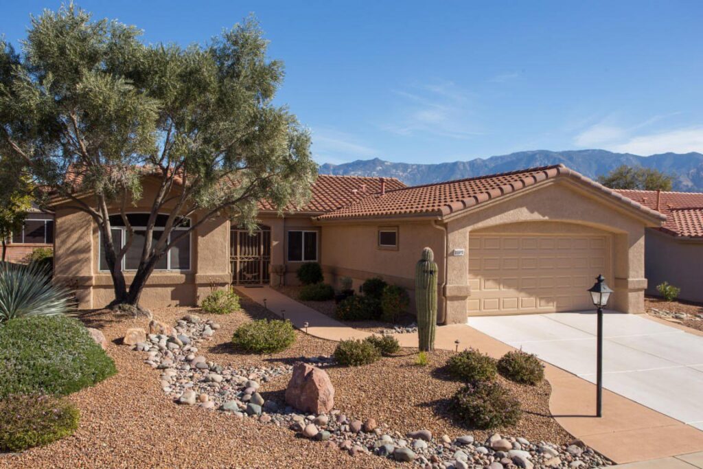 A beautiful residential home featuring a beige garage door and desert landscaping, installed by Johns Garage Doors in Tucson, AZ.