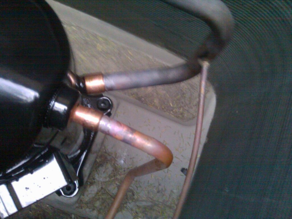 Close-up of the base of an outdoor AC unit showing line connections during service by J AND J HVAC L.L.C in Mesa, AZ