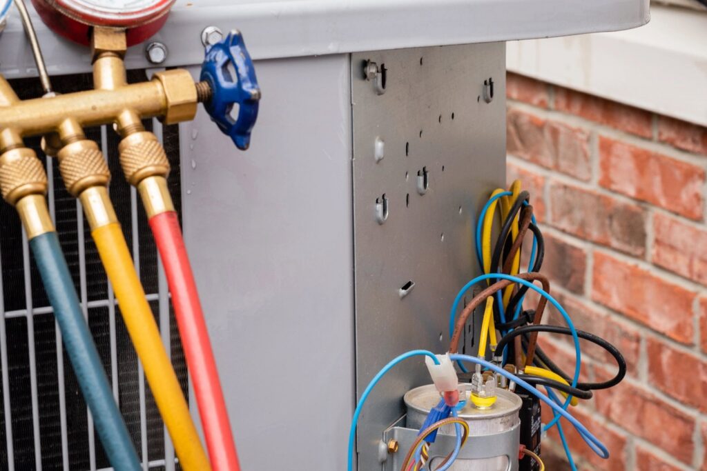 Close-up of electrical components and wiring inside an outdoor AC unit during repair by Wyles Heating & Air Conditioning Inc. in North Canton, OH.