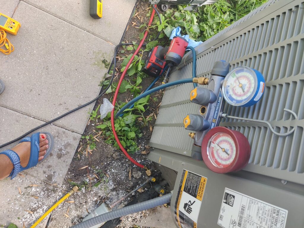 An outdoor AC unit undergoing a refrigerant check with manifold gauges by Chief/Bauer Service Experts in Champaign, IL.