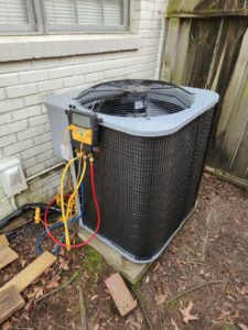 An outdoor AC unit being serviced with manifold gauges by Faith Heat and Cool in West Monroe, LA