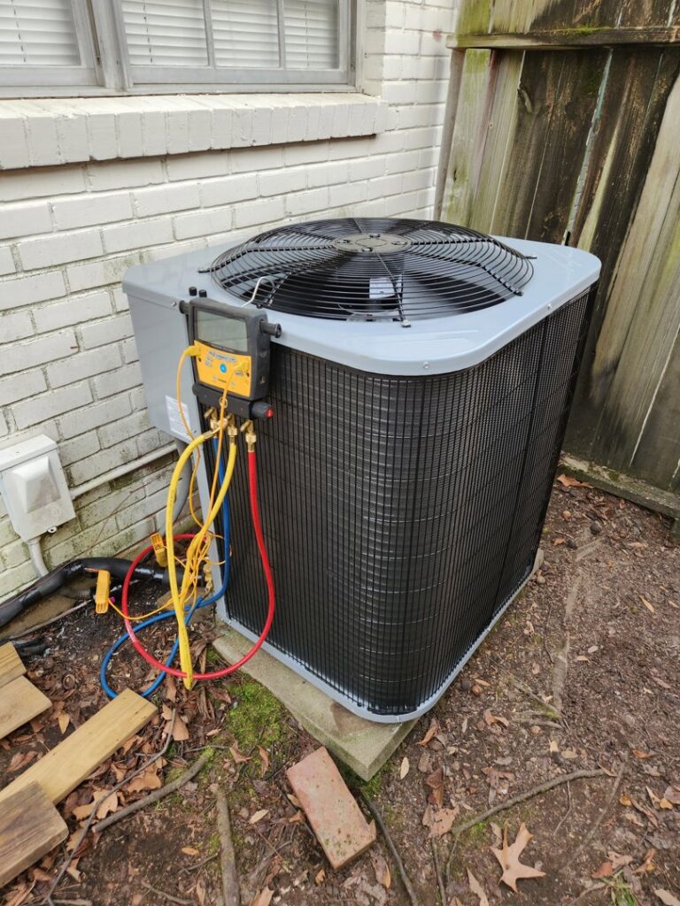 An outdoor AC unit being serviced with manifold gauges by Faith Heat and Cool in West Monroe, LA