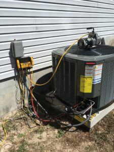 An outdoor AC unit undergoing service or installation with gauges and a vacuum pump connected by 911 Heating and Air Conditioning Co.,Inc. in Mary Esther, FL