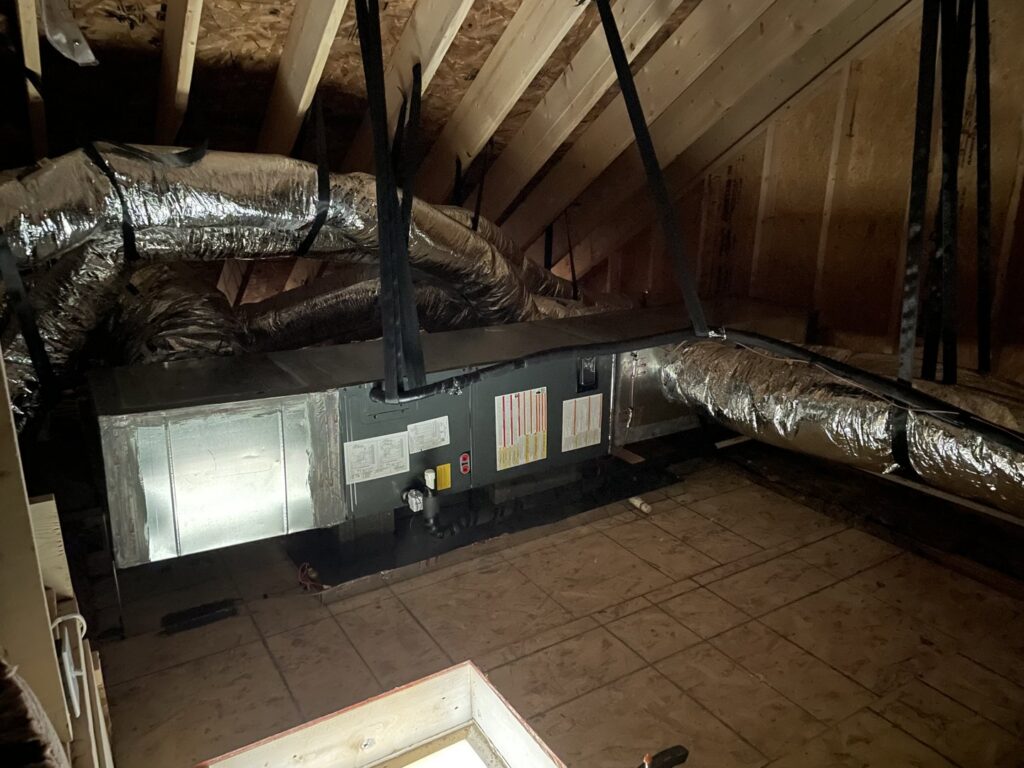 An HVAC air handler unit suspended in an attic with new ductwork installed by Luciano's Air Services in Durham, NC.