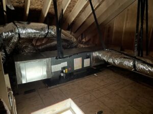An HVAC air handler unit suspended in an attic with new ductwork installed by Luciano's Air Services in Durham, NC.