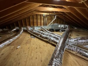 An HVAC air handler unit and extensive ductwork installation visible in an attic, performed by Indoor Expert Heating & Cooling in Paterson, NJ.