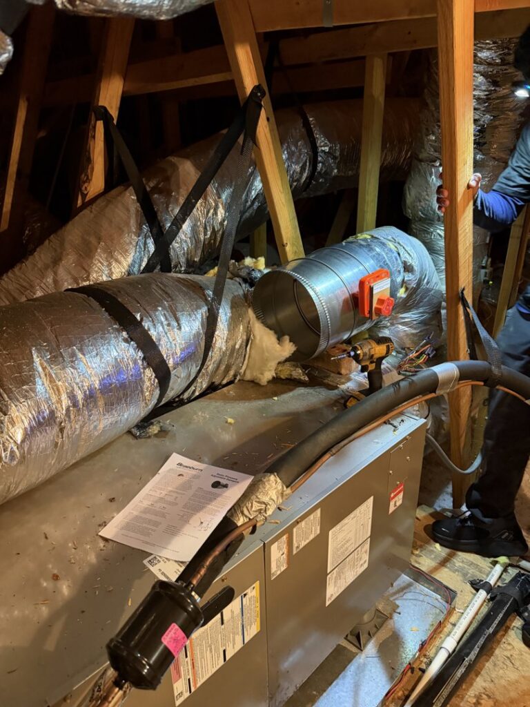 An HVAC air handler unit and ductwork being installed in an attic by Green Dot Heating & Air in Wilmington, NC.