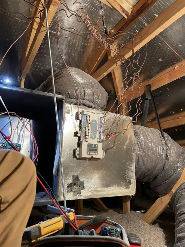 An HVAC air handler unit with wiring and ductwork installed in an attic by Kaluas HVAC Mechanical Services in Phoenix, AZ