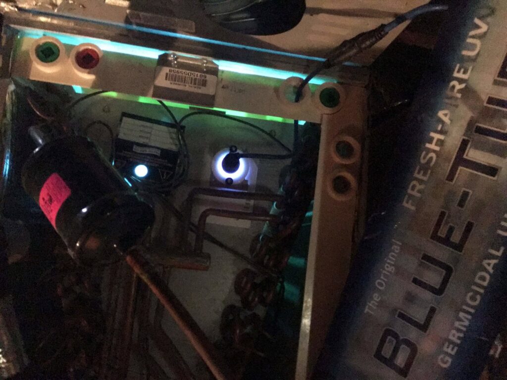 Inside an HVAC air handler showing a germicidal UV light operating, installed by West Tennessee Heat & Air in Memphis, TN