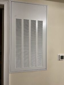 A white HVAC air return vent or filter access panel installed on a wall by Delta Heating, Cooling, Plumbing in Wilson, NC.