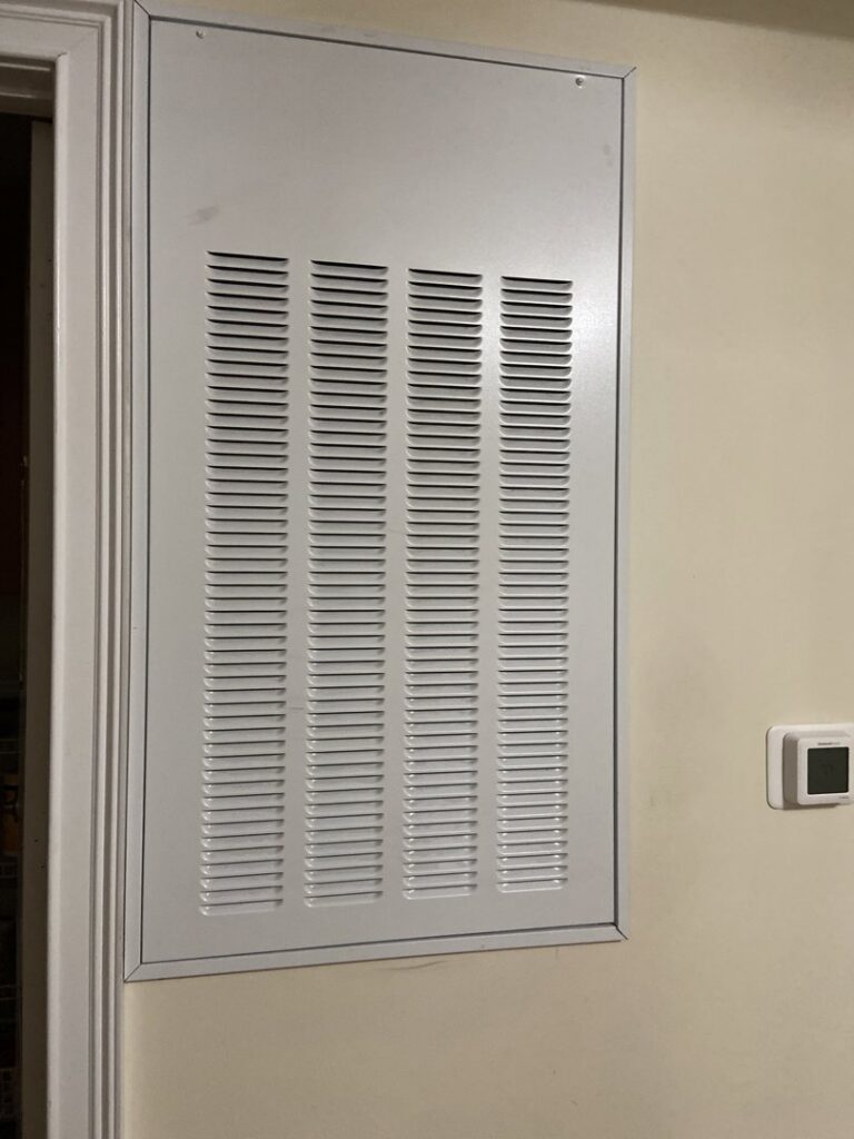 A white HVAC air return vent or filter access panel installed on a wall by Delta Heating, Cooling, Plumbing in Wilson, NC.