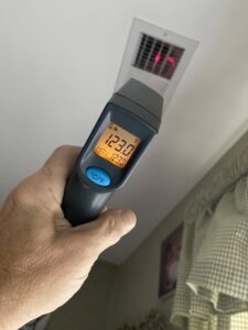 An HVAC technician checking air vent temperature with an infrared thermometer by Reasonable Air, LLC in Summerville, SC.