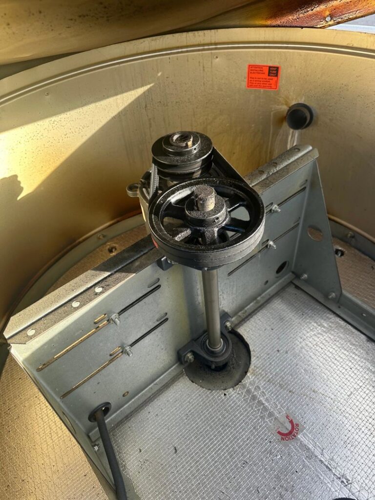 A close-up view of a belt-driven fan or blower mechanism within an HVAC unit, showing internal components serviced by Air Casablanca Heating & Cooling in Myrtle Beach, SC.